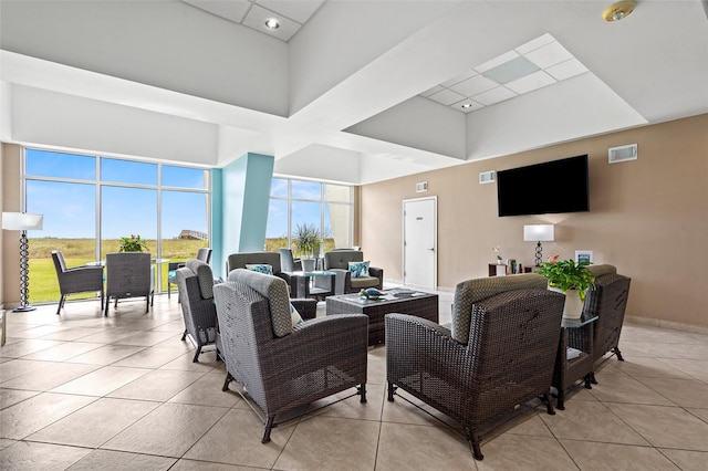 living room featuring light tile patterned flooring, visible vents, and a towering ceiling