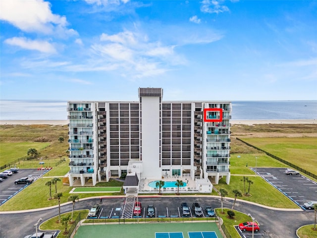 view of building exterior with uncovered parking and a water view