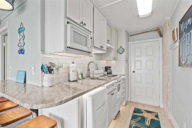 kitchen with white appliances, a breakfast bar area, wood finish floors, a sink, and decorative backsplash