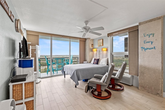 bedroom featuring multiple windows, wood finished floors, a wall of windows, and access to outside