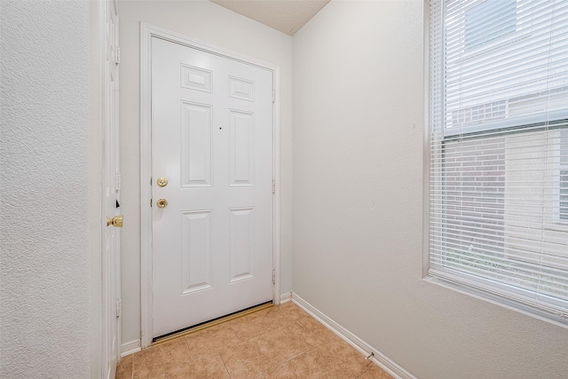 doorway to outside with light tile patterned floors, baseboards, and a textured wall