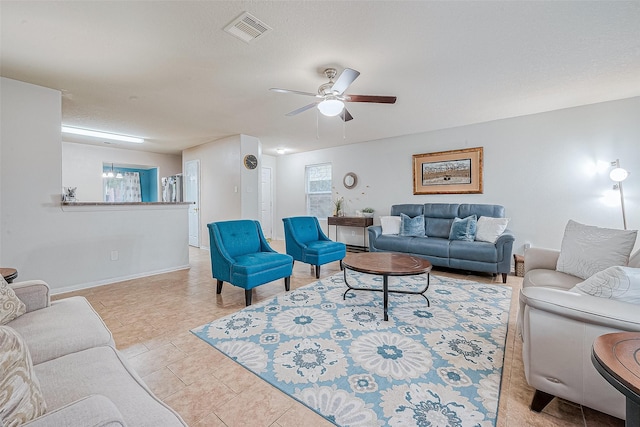 living area with a ceiling fan, baseboards, visible vents, light tile patterned flooring, and a textured ceiling