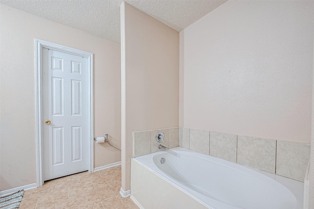 bathroom with tile patterned floors, baseboards, a textured ceiling, and a bath