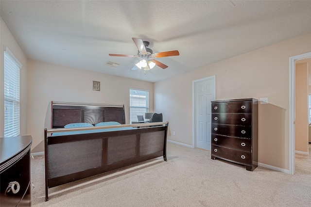 bedroom with visible vents, baseboards, ceiling fan, carpet flooring, and a textured ceiling