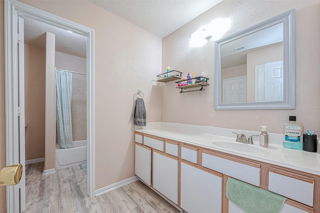 full bathroom with vanity, wood finished floors, visible vents, shower / tub combo, and a textured ceiling