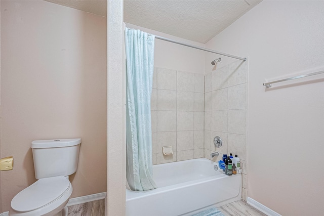 bathroom featuring toilet, shower / bath combo, a textured ceiling, wood finished floors, and baseboards