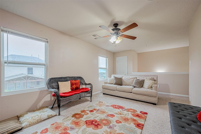 living area featuring visible vents, baseboards, ceiling fan, and carpet flooring