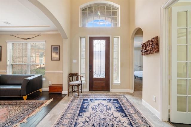 foyer with arched walkways, visible vents, and baseboards