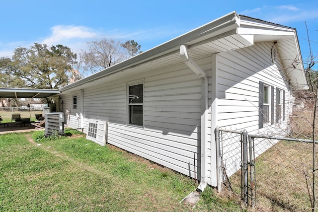 view of side of property with central air condition unit, a lawn, fence, and a gate