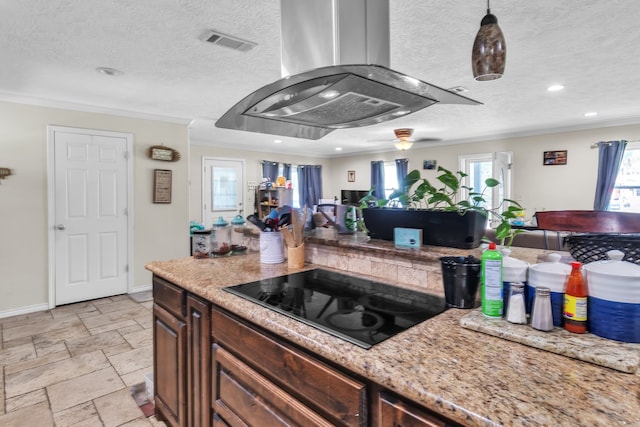 kitchen with visible vents, island exhaust hood, stone tile floors, crown molding, and black electric stovetop