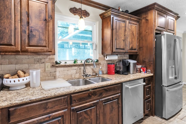 kitchen featuring light stone counters, a sink, appliances with stainless steel finishes, pendant lighting, and tasteful backsplash