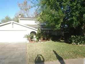 view of front of house featuring concrete driveway, an attached garage, and a front lawn