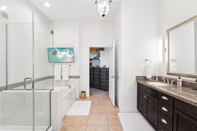 bathroom featuring tile patterned floors, a garden tub, a stall shower, a spacious closet, and vanity