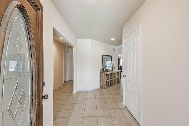 hallway with light tile patterned floors, baseboards, a textured ceiling, and recessed lighting