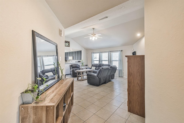 living area featuring visible vents, ceiling fan, vaulted ceiling, a textured wall, and light tile patterned flooring