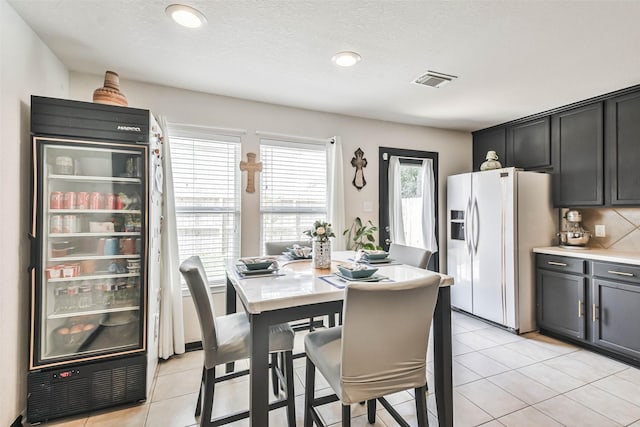 dining area featuring visible vents, beverage cooler, a textured ceiling, and light tile patterned flooring