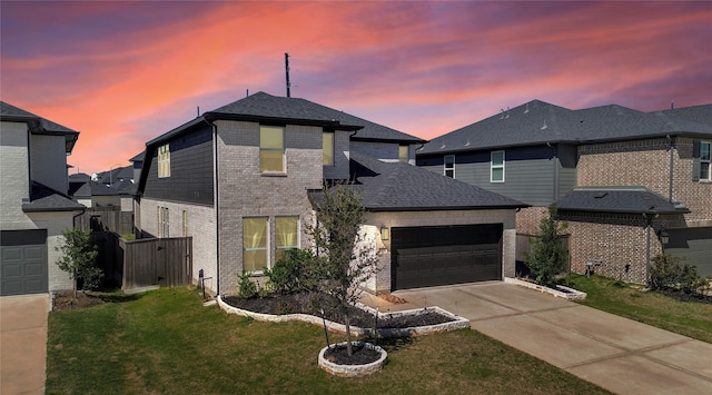 view of front of house with roof with shingles, concrete driveway, a front lawn, a garage, and brick siding