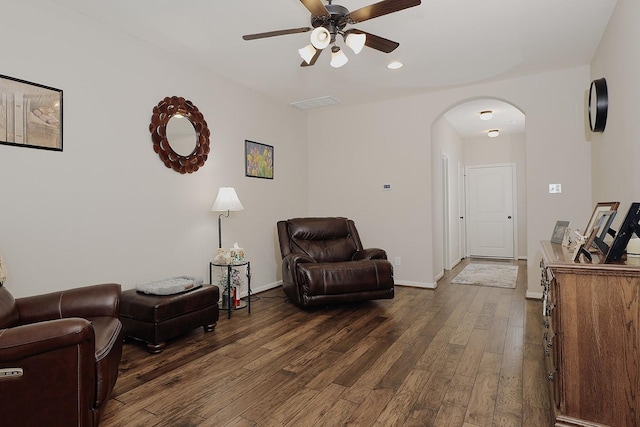 sitting room featuring dark wood-style floors, visible vents, baseboards, arched walkways, and ceiling fan