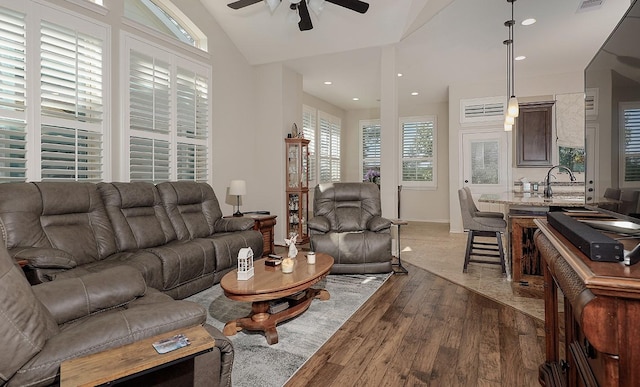 living area with a ceiling fan, wood finished floors, visible vents, recessed lighting, and vaulted ceiling