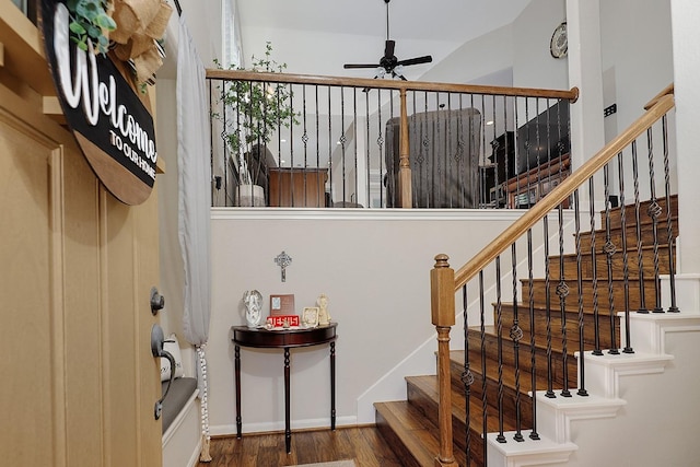 staircase featuring wood finished floors, baseboards, and ceiling fan