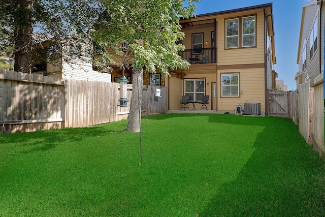 rear view of house featuring central air condition unit, a balcony, a fenced backyard, and a lawn