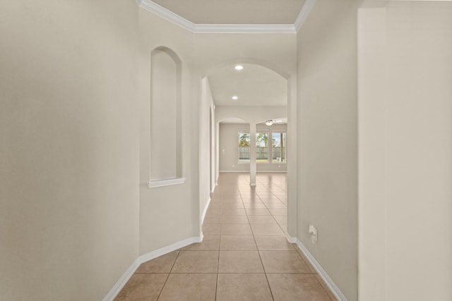 hallway featuring baseboards, ornamental molding, light tile patterned floors, recessed lighting, and arched walkways