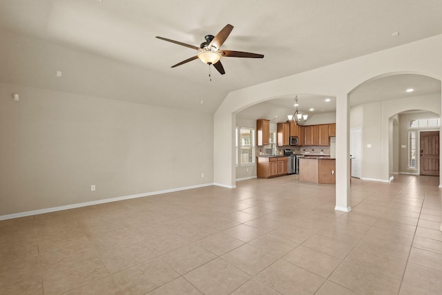 unfurnished living room with lofted ceiling, light tile patterned floors, ceiling fan with notable chandelier, and baseboards