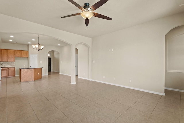 unfurnished living room featuring ceiling fan with notable chandelier, light tile patterned floors, recessed lighting, and baseboards