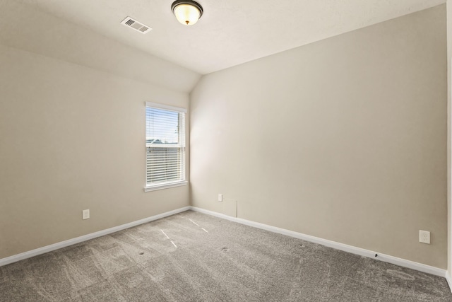 carpeted spare room with visible vents, lofted ceiling, and baseboards