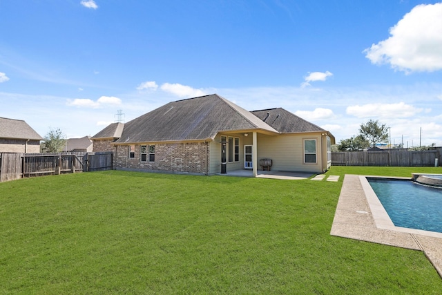 rear view of property with brick siding, a fenced in pool, a yard, a fenced backyard, and a patio area