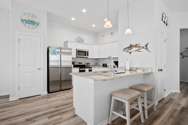 kitchen with a sink, appliances with stainless steel finishes, a breakfast bar area, a peninsula, and white cabinets