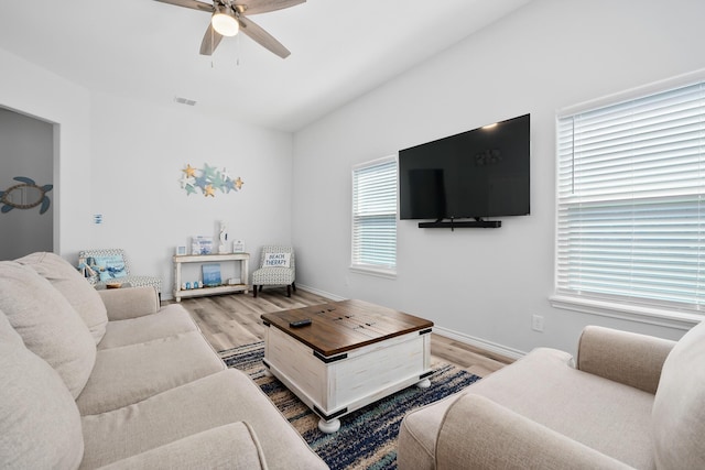 living area featuring baseboards, light wood-style floors, visible vents, and ceiling fan