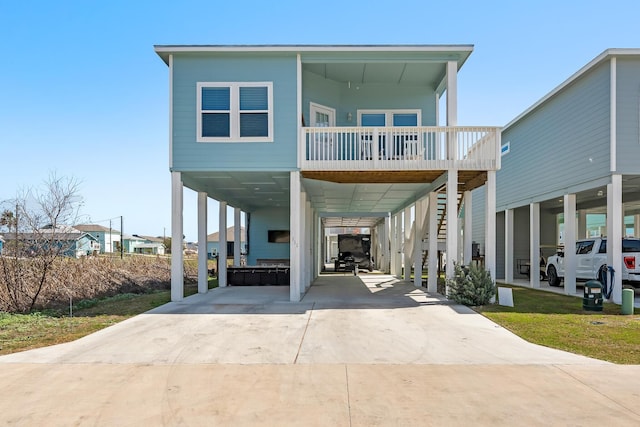 coastal home featuring stairway, a carport, and concrete driveway