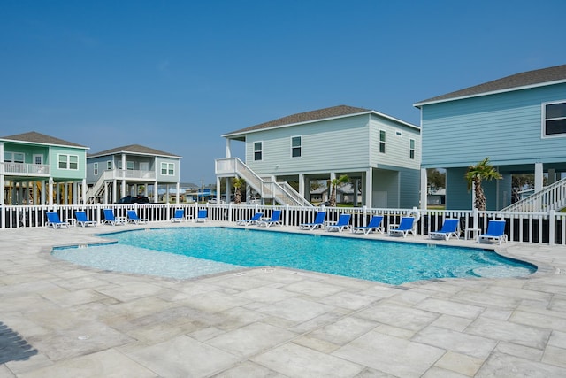 community pool with stairs, a patio, and fence