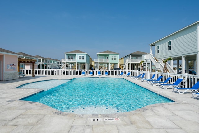 community pool with a patio, fence, and a residential view