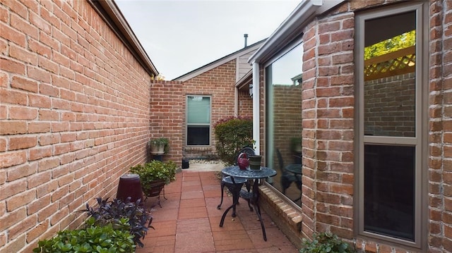 view of side of property with brick siding and a patio area