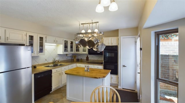 kitchen with an inviting chandelier, a sink, black appliances, wood counters, and tasteful backsplash