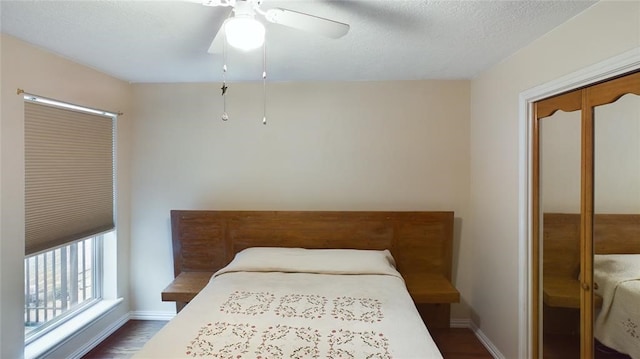 bedroom with baseboards, a ceiling fan, dark wood-style flooring, and a textured ceiling