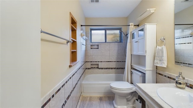bathroom featuring toilet, tile walls, visible vents, wood finished floors, and shower / tub combo with curtain