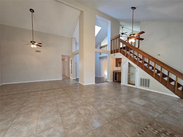 unfurnished living room with high vaulted ceiling, a ceiling fan, stairs, and visible vents