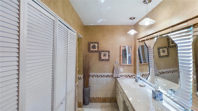 bathroom with tile patterned floors, a closet, tile walls, wainscoting, and vanity