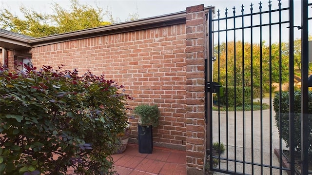 view of exterior entry with brick siding and a gate