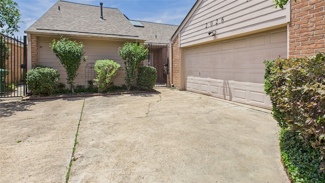 2026 Ashford Hollow Ln, Houston, TX 77077 - view of side of property with roof with shingles, brick siding, concrete driveway, a gate, and fence
