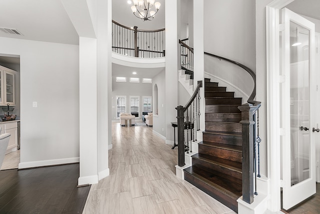 foyer with visible vents, baseboards, stairs, light wood-style floors, and a notable chandelier