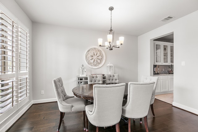 dining area featuring a notable chandelier, visible vents, baseboards, and dark wood-style flooring