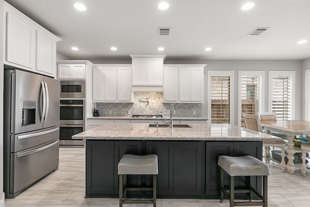 kitchen with visible vents, white cabinets, stainless steel appliances, and a sink