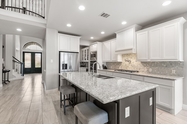 kitchen featuring visible vents, a sink, decorative backsplash, french doors, and appliances with stainless steel finishes