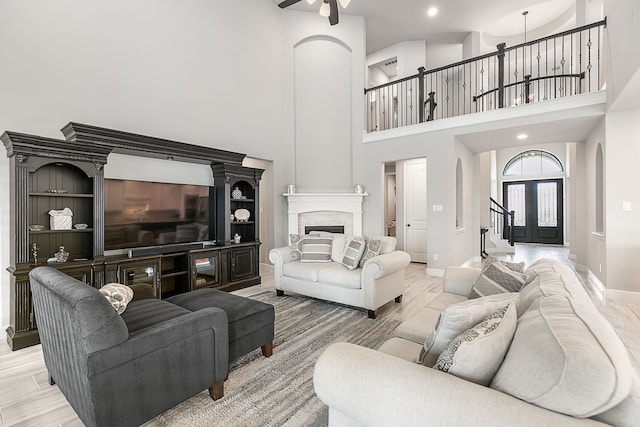 living room featuring baseboards, light wood-style flooring, a fireplace, arched walkways, and a ceiling fan