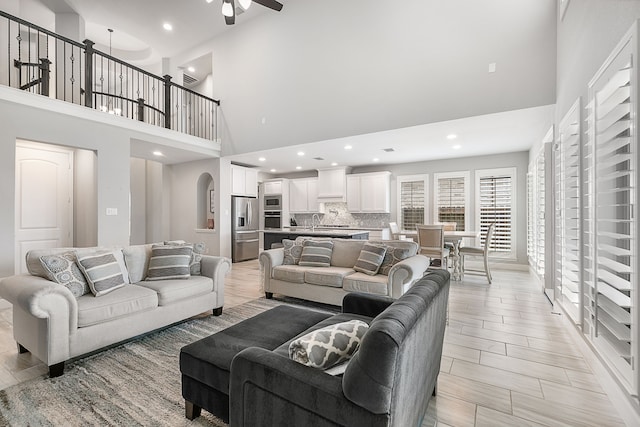 living room with arched walkways, recessed lighting, a high ceiling, and ceiling fan