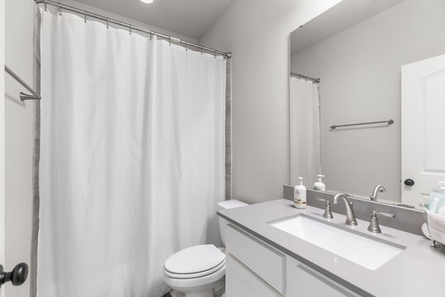 full bath with vanity, toilet, and a textured wall